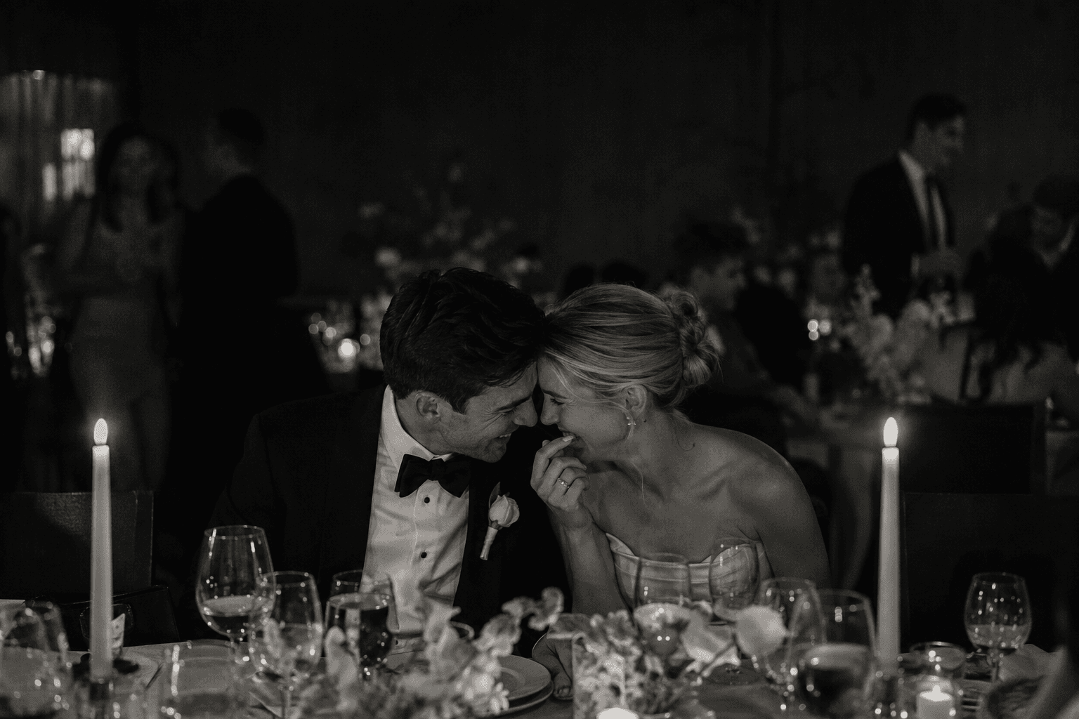 Newlyweds laughing at an intimate candlelit dinner